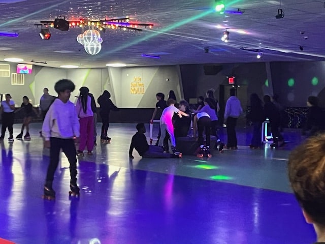 Kids skating on rink with black lights on. 