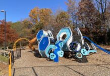 Photo of a blue outdoor climbing center with a yellow playground slide.