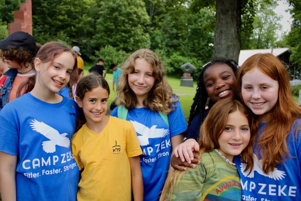 Children pose and smile at the camera with their arms around one another.