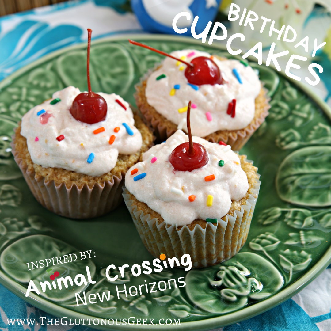Photo of three homemade iced vanilla cupcakes on a decorative green ceramic plate. Each cupcake is topped with light pink frosting, rainbow sprinkles and a maraschino cherry. White text in the top right corner reads "BIRTHDAY CUPCAKES" and white text at the bottom reads "Inspired By Animal Crossing: New Horizons." Below that, white text reads "www.theGluttonousGeek.com."