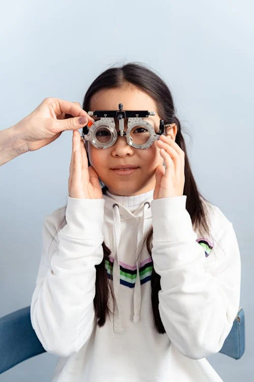 Stock photo of a young girl getting her eyes measured with an eye device.