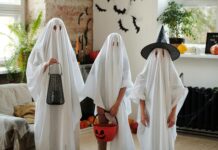 10 Safety Tips for Trick-or-Treaters Photo of three people standing in a row in a living room wearing white ghost costumes with holes cut for their eyes. The one on the left is holding a black lantern, the center one is holding an orange plastic pumpkin basket and the one on the right is wearing a black pointed witch's hat.
