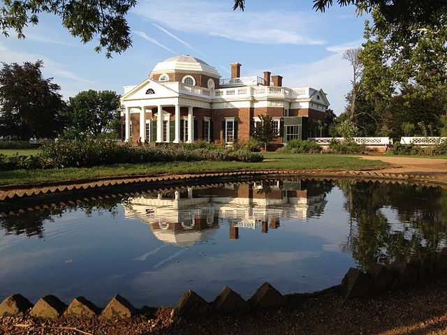 Photo of the exterior of Monticello, a large brick mansion, with a pond in front.
