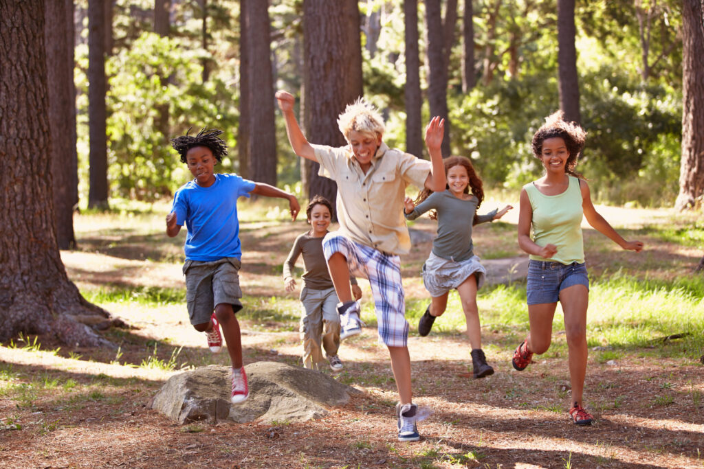 Stock photo of half a dozen kids running and jumping in the woods.