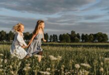 15 Things To Do in Your Backyard Stock photo of two young girls running through a field holding hands.