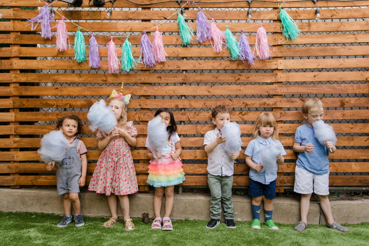 Stock photo of six children standing in a row holding cotton candy at a kids' birthday party.