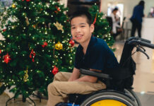 Inclusive Charities to Support During the Holidays A child in a wheelchair by a Christmas tree