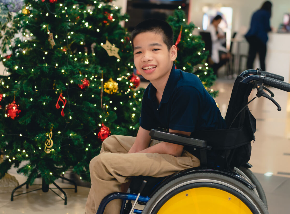 A child in a wheelchair by a Christmas tree