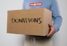 A volunteer holding a box labeled donations