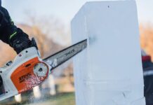 Person carving a block of ice with a chainsaw