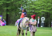 A child rides a horse dressed as a unicorn for the Fairy & Gnome Home Festival in Solomons, MD
