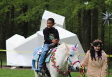 A child rides a "unicorn" at the Fairy & Gnome Home Festival