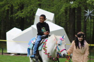 A child rides a "unicorn" at the Fairy & Gnome Home Festival