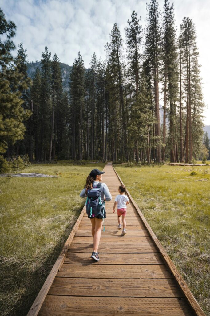 Parent and child hiking on a wooden trail through a park