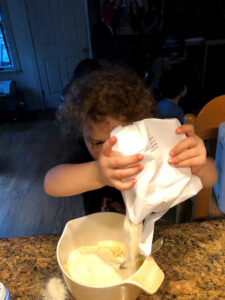 A child pours cornbread mix while cooking in the kitchen