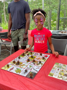 Girl in insect face paint looking at a display of bugs