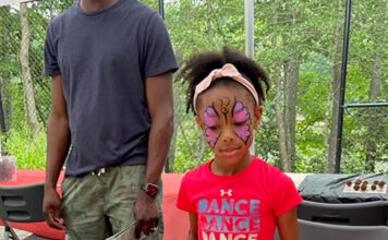 Girl in insect face paint looking at a display of bugs