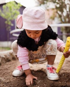 A girl playing outside in the dirt