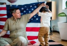A woman and child interact playfully under an American flag indoors