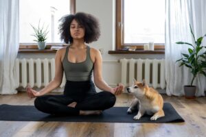 A woman meditating with a dog