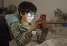 Cautions for Screen Time A boy wrapped in a blanket while using a smartphone