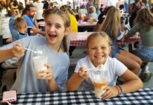 2026 Maryland State and County Fairs Two girls sit at a checkered picnic table eating Maryland State Fair treats.