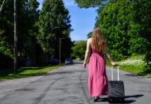 A woman walks with a roller suitcase down the street