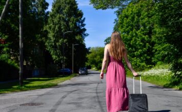 A woman walks with a roller suitcase down the street