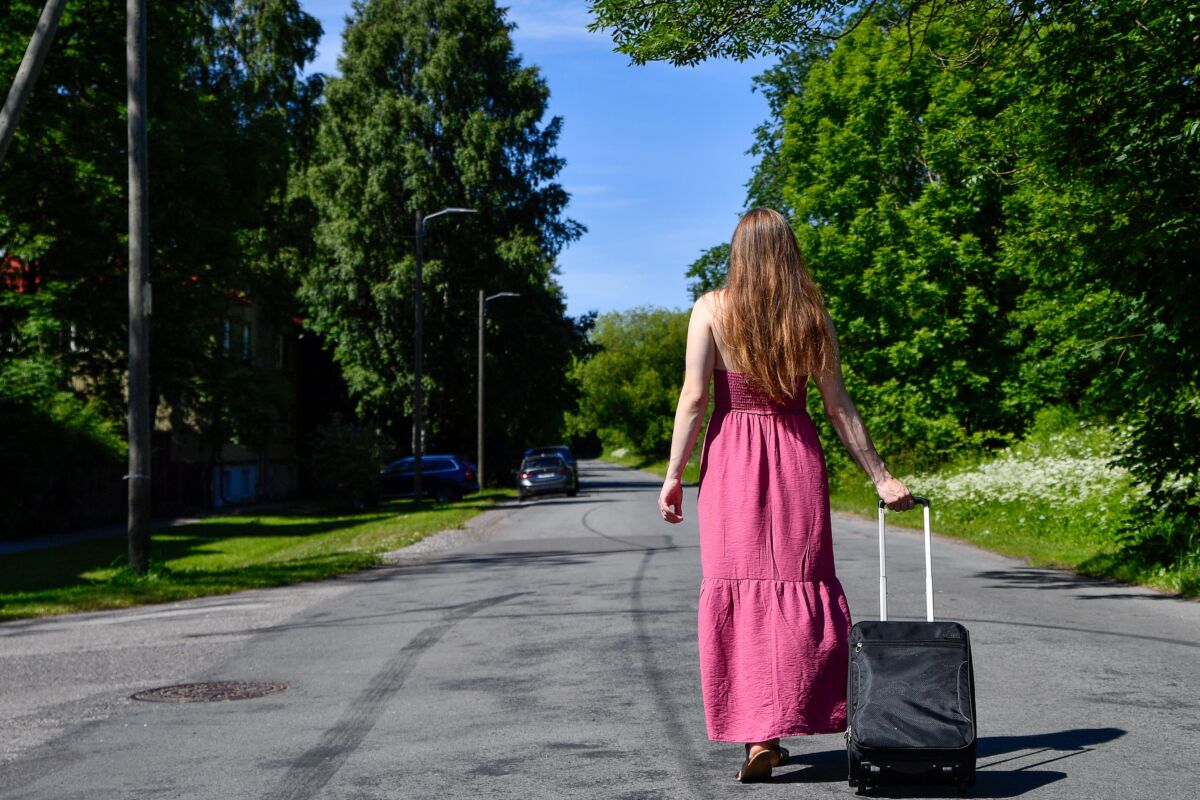 A woman walks with a roller suitcase down the street