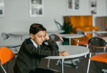 Boy sitting alone at a table looking sad